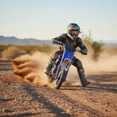 Kid riding a blue pit bike wearing full protective motocross gear, helmet, and boots.