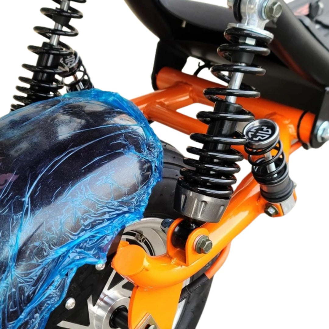 Close-up of a motorcycle suspension system with orange metal components and black shock absorbers.